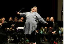 A person singing with a baton in front of a group of peopleDescription automatically generated